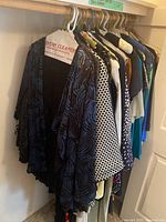 Photo showing front section of hanging dresses and jackets, including black lace cardigan.
