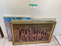 Six framed art pieces leaning against wall, front view