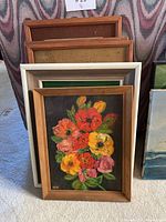 Front view of stacked paintings showing multi-colored poppy bouquet in brown wood frame