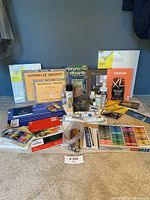 Overview of assembled art supplies including canvases, papers, paint tubes, pastels, brushes, palettes, and instructional books.