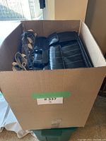 Box container holding multiple eel skin and leather bags and purses, showing tops of bags in brown, beige, and black tones.