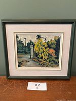 Front view of framed painting showing scene with lamppost, gate and foliage