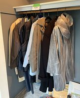 Seven hanging coats and jackets in various colors grouped on a rail