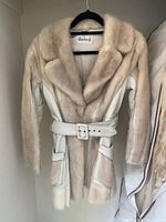 Front view of vintage Woodwards fur and leather jacket, showing fur collar, leather sleeves, front pockets, and belt.