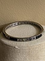 Front view of antique sterling silver bangle bracelet showing pyramid cut crystal stones and engraved patterns.