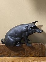 Side view of the cast iron piggy bank showing the pig sitting with detailed legs and curled tail