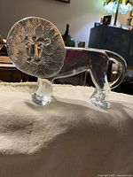 Side angle showing textured circular mane, stylized lion face, and intact body with clear glass legs and curled tail.