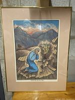 Full view of framed vintage artwork depicting the Burning Bush biblical scene with a man in blue kneeling on stone steps and mountains in background.