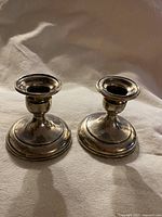 Pair of vintage Birks sterling silver candle holders with classic rounded base and flared candle cup tops, showing overall polished finish and slight tarnish.
