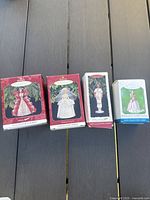 Four boxed Hallmark Keepsake Barbie holiday ornaments displayed on wood table, showing front panel artwork and branding