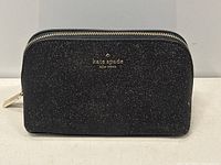 Front view of the black glittery Kate Spade makeup bag with gold-tone zipper and logo.