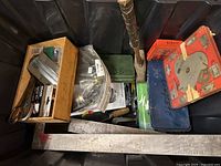 Photo showing a bin full of vintage tools including a wooden hammer, metal tools, and labeled boxes.