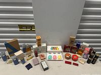 Lot view showing assortment of soaps and perfumes including Avon bottles, boxed soaps, and decorative containers.