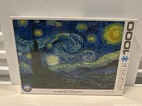 Image of the sealed box of a 1000-piece jigsaw puzzle showing the artwork 'Starry Night' by Vincent van Gogh from Pomegranate brand.