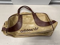 Front view of vintage Adidas bag showing main logo, tan and brown design, and zipper closure.