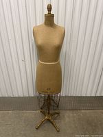 Front view of dress form showing fabric-covered torso, size 12 label, wired lower cage and cast iron tripod base