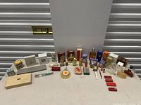 Full lot showing multiple vintage perfume bottles, boxed items, accessories arranged on table in front of storage unit door