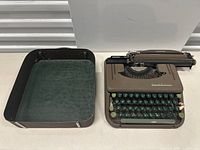 Full view of typewriter and open carrying case with green inner lining.