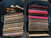 Two large plastic bins filled with numerous vinyl records in various album covers, showcasing the size and volume of the collection