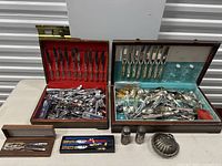 Overview of two vintage flatware sets in their original cases and loose flatware, plus small collectibles.