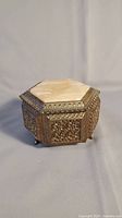 Closed hexagonal music box with gold metal filigree and marble inlay lid.