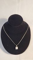 Sterling silver serpentine chain necklace displayed on black bust stand, featuring a clear square multifaceted pendant.