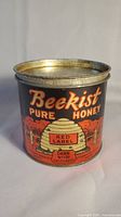 Front side of vintage Beekist Pure Honey tin can showing label and beehive illustration.