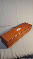 Closed wooden box showing top lid and decorative inlay on front panel
