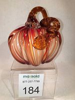 Front view of swirled glass pumpkin with label showing lot number