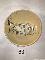 Top view of the cream-colored stoneware bowl with a hand-painted rabbit and bee design inside.