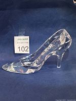 Side profile of Bohemia lead crystal Cinderella glass slipper on blue cloth background showing heel and toe details.