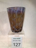 Front view of hand blown mocha graniti opalescence glass tumbler on clear stand.