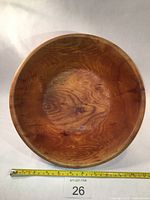 Top view of the large wooden bowl showing the grain pattern and natural wood knots inside the bowl along with a measuring tape to indicate size.