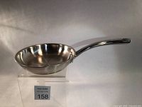 Side angle view of a polished stainless steel sauce pan with long handle, showing the interior and reflective exterior finish.