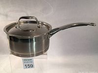 Side view of Lagostina Merano stainless steel sauce pan with lid on a clear stand, showing handle with silicone grip and smooth exterior finish