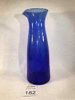 Full view of a tall cobalt blue vintage glass pitcher with crackle texture, showing the shape and color clearly.