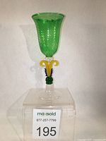 Front view of Murano Venetian wine goblet showing green swirl pattern on cup, colorful yellow and blue scroll stem, clear dome base.
