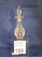 Front and side views showing the American Brilliant Cut Glass cruet with decorative stopper, highlighting the cut patterns and asymmetrical lip.