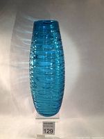 Full view of a tall teal glass vase showing applied horizontal glass thread spirals from base to top tapered opening.