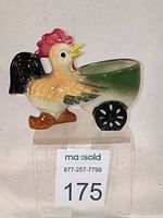 Full view of the ceramic rooster wheeled planter showing vibrant colors and large black wheel with white floral detail.