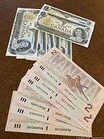 Front and back views of Canadian $1 and $2 bills, showing portraits of Queen Elizabeth II and birds on $2 bills.