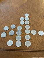 Full overview of 19 assorted Canadian dollar coins arranged on wooden surface, showcasing size and general appearance.