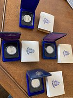 Four Canadian dollar coins in blue velvet presentation cases along with white outer boxes stamped 'Canada'