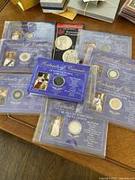 Eight Canadian Mint Portraits of Canada coins in plastic sleeves on a table with blue backing and portraits of monarchs.