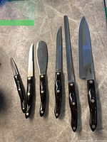 Six utensils arranged side by side on countertop showing full set