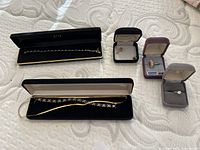 Overview showing two long items (snake chain and tennis bracelet) plus three jewelry boxes with rings and earrings