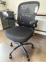 Front angle view of black mesh back office chair with fabric seat and armrests on caster wheels.