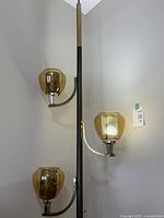 Photo of entire pole lamp with three amber glass shades and metal pinhole mesh chimneys, unlit.
