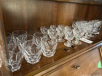 Eight Kathleen pattern tumblers arranged in two rows on wood shelf