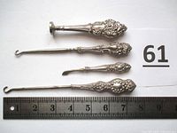 Four sterling silver vanity items laid out with ruler showing sizes, ornate beaded scroll handles visible